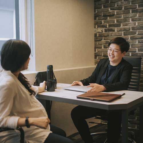 Pregnant woman talking to another woman in office environment