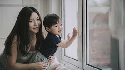 Young mother with child looking out window
