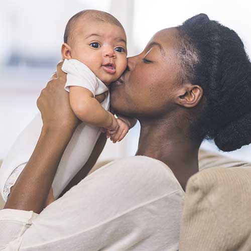 Young African American woman giving her baby a kiss