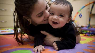 Young mother playing with baby on floor