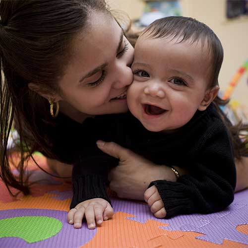 Mother and baby crawling on floor, smiling